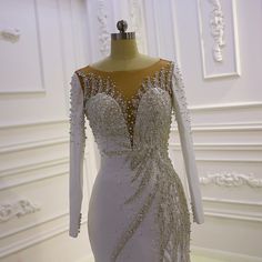 a wedding dress on display in a white room with gold trimmings and beading