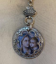 An antique French image of Madonna and Child is sealed into an ornate bezel. It hangs below  a vintage metal piece on silvery chain accented with a small cross. Adjusts 21 to 23". Vintage Necklaces With Miraculous Medal, Vintage Jewelry With Miraculous Medal For Memorial, Antique Miraculous Medal Necklace As Gift, Vintage Crucifix Necklace With Miraculous Medal, French Images, Black Madonna Necklace, Assemblage Necklace, Small Crosses, Madonna And Child