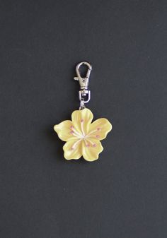 a yellow flower shaped keychain on a black surface