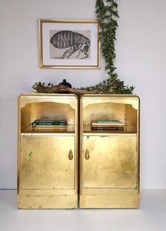 a gold cabinet with books and plants on top