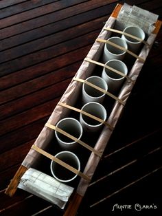 four empty cups sitting on top of a wooden table next to a paper towel holder