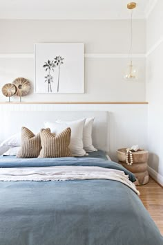 there is a bed with blue sheets and pillows on the headboard in this bedroom