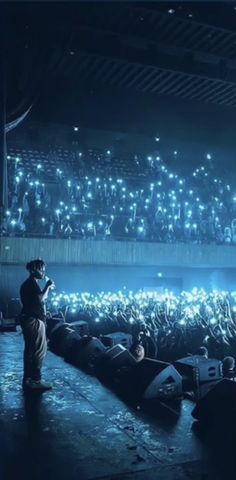 a man standing on top of a stage in front of an audience at a concert