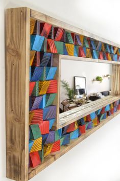 a mirror that is on the side of a wooden frame with colorful paper pieces in it