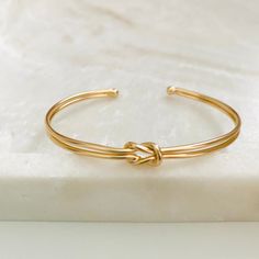 This is ideal if you are looking for a gift to impress a mom. Our knot bracelet is designed for her; it is a fine and delicate piece; we have two styles available: the knot bracelet and the mom bracelet; they are made with layers of 18k gold-filled, which means that with good use of your garment, it can last a long time.  Product: - Adjustable Knotted Bracelet - Adjustable Mom Bracelet - Item Details: - Material: 18k Gold Filled - Bangle Size: Adjustable -Width: 4 mm - Benefits:  Water & Tarnish Elegant Bangle Bracelet For Best Friend Gift, Gold Cuff Bracelet For Bridesmaid Gift, Adjustable Gold Bangle Bracelet As Gift, Adjustable Gold Bangle Bracelet Gift, Adjustable Bangle Bracelets For Mother's Day, Adjustable Bangle Bracelet For Mother's Day, Adjustable Bangle As A Gift, Adjustable Bangle Bracelets For Bridesmaid Gift, Dainty Bangle Cuff Bracelet As Gift