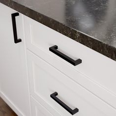 a kitchen counter with black handles and white cabinets