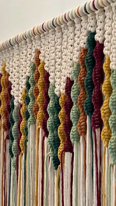 the wall is decorated with multicolored crocheted yarns and tassels