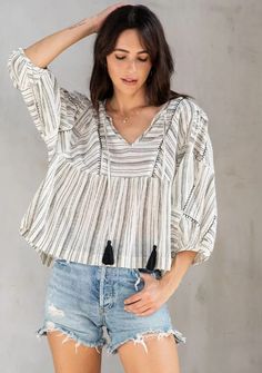 An ultra-flowy bohemian top made for warm days and nights. Designed in a cotton slub stripe, featuring exaggerated puff sleeves, tassel neckties, and a bib front. The hand-stitched embroidery elevates this effortless boho top. Bohemian Cotton Blouse With Back Tassel Tie-up, Striped Cotton Blouse For Vacation, Casual Cotton Blouse With Back Tassel Tie-up, Bohemian Striped Cotton Tops, Bohemian Peasant Top With Tassel Ties For Vacation, Bohemian Striped Tops For Vacation, Bohemian Peasant Top With Tassel Ties For Summer, Bohemian Peasant Top With Tassel Ties For Beach, Chic Beach Tops With Tassel Ties