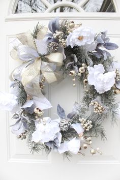 a wreath with white and blue flowers hanging on a door