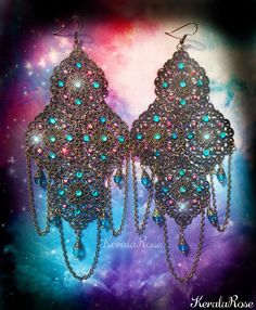 These exotic chandelier earrings are made with filigree pendants decorated with Teal & Fuchsia Swarovski rhinestones. Draped chains and Teal blue crystal beads hang from the design. There are 72 hand set Swarovski and Preciosa Rhinestones on this pair!  These can be worn everyday comfortably because they are lightweight for their size!  They're available with Posts, Clip-Ons or French Wires. Metal Finishes Available: -Bronze (as pictured) -Silver -7" Long (including piercing) x 3" Wide -0.4 oz.. Affordable Blue Bohemian Chandelier Earrings, Bohemian Jeweled Crystal Earrings For Party, Bohemian Jeweled Crystal Dangle Earrings, Bohemian Turquoise Chandelier Earrings For Party, Turquoise Bohemian Chandelier Earrings For Party, Jeweled Dangle Chandelier Earrings, Bohemian Blue Jeweled Earrings, Bohemian Crystal Earrings For Party, Bohemian Dangle Chandelier Earrings For Parties