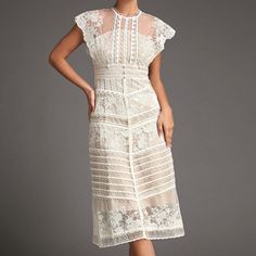 This lace midi dress will fill any of your little white dress needs, from your bridal shower to your after party! Sheer mesh, embellished with gorgeous lace creates a high, round neck and a fitted bodice with scalloped edges and cap sleeves. A high, fitted waist sits above an A-line midi skirt that has tiers of scalloped edges. Style this with strappy heels and simple accessories to complete the look.No StretchMedium WeightSize runs small,recommend one size upFabric: 100% Polyester,Lining: 100% Feminine Lace Bodice Midi Dress For Wedding, Feminine Delicate Lace Midi Dress For Wedding, Elegant White Midi Dress With Lace Top, Wedding Lace Dress With Lace Patchwork In Midi Length, Knee-length Lace Patchwork Wedding Midi Dress, Knee-length Lace Patchwork Midi Dress For Wedding, Midi-length Lace Wedding Dress With Delicate Details, Feminine Lace Patchwork Dress For Wedding Guest, Elegant White Midi Dress With Lace Bodice