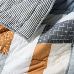 an unmade bed with two pillows on top of it and a striped comforter