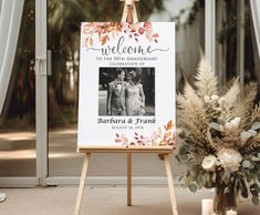 an easel with a welcome sign and flowers on it