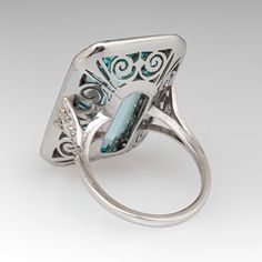 This mazing vintage cocktail ring is centered with one (1), bezel set, emerald cut natural aquamarine that is bordered with thirty-six (36), bead set, round single cut diamonds. The shoulders of the ring are each accented with three (3), bead set, round single cut diamonds. The gemstones are bordered with milgrain edging. The ring measures 28.9mm X 18.7mm at the top, rises 9.1mm above the finger, tapering to 1.7mm wide and 1.3mm thick at the base of the shank. It is currently a size 7. Art Deco Ring With Bezel Setting, Art Deco Jewelry With Gemstone Accents For Anniversary, Art Deco Anniversary Jewelry With Gemstone Accents, Fine Jewelry With Accent Stones For Collectors, Elegant Turquoise Multi-stone Rings, Art Deco Emerald Ring In Baguette Cut White Gold, Rectangular Silver Emerald Ring For Formal Occasions, Rectangular Aquamarine Jewelry For Wedding, Elegant Octagon Multi-stone Ring