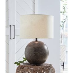 a lamp that is sitting on top of a table with a white shade over it