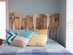 a bed topped with lots of pillows next to wooden boards mounted on the headboard