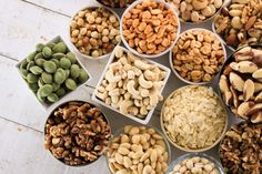 several bowls filled with nuts on top of a wooden table