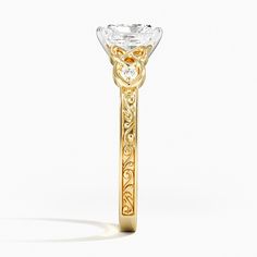 a yellow gold and white diamond ring on a white background with the center stone surrounded by intricate filigrees