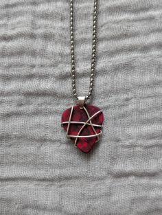 a red heart shaped pendant on a silver ball chain with an arrow in the middle