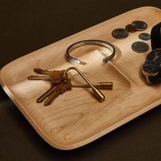 a wooden tray with keys and coins on it