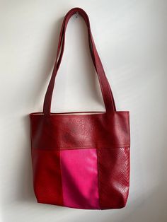 Unique handmade faux-leather tote bag in red and pink.  Bag measures 15 inches wide x 16 inches tall Total height including strap is 28 inches Cotton lining. Features two interior pockets Red Rectangular Bag With Large Capacity, Pink Large Capacity Leather Bag, Large Capacity Pink Leather Bag, Large Capacity Red Faux Leather Bag, Large Capacity Red Rectangular Bag, Red Square Shoulder Bag With Adjustable Strap, Red Faux Leather Shoulder Bag With Double Handle, Red Rectangular Faux Leather Bag, Red Rectangular Bucket Bag With Large Capacity