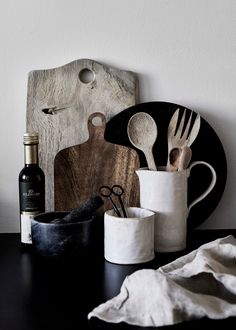 kitchen utensils are sitting on a table next to a cutting board and wine bottle