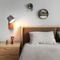 a bed with white sheets and pillows next to two wall mounted clocks on the wall