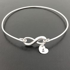 "This is a small sized dainty & delicate sterling infinity which I transform into an infinity bangle bracelet with sterling silver bangle band. PURITY OF METAL: This makes a great gift for teen girls since all elements of the bracelet are sterling silver. Sterling silver is suggested for teen girl jewelry because of the purity of the metal. It's great for adults too. PERSONALIZED OPTIONS: Select optional initial charms (up to 3) to dangle from the infinity loop. I can also add charms to the Silver Infinity Jewelry, Minimalist Bangle Jewelry For Valentine's Day, Minimalist Sterling Silver Bracelets For Bridesmaids, Dainty Sterling Silver Charm Bracelet For Personalized Gift, Minimalist Silver Infinity Bracelet, Elegant Silver Charm Bracelet For Personalized Gift, Simple Adjustable Sterling Silver Bracelets, Elegant Sterling Silver Charm Bracelet For Personalized Gift, Personalized Infinity Jewelry For Bridesmaid Gift