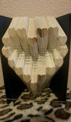 an origami heart made out of book pages sitting on top of a leopard print rug