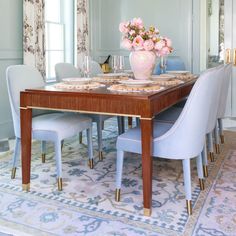 a dining room table with blue chairs and pink flowers