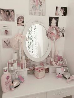 a white dresser topped with a mirror and lots of pink items on top of it