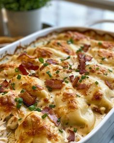 a casserole dish with cheese, bacon and green onions in it on a table