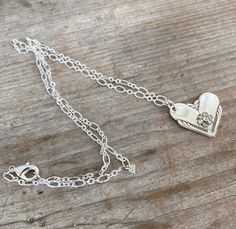 This gorgeous upcycled spoon heart necklace was made by marrying the ends of two silverplate spoon handles. The heart pendant was then adorned with a rhinestone flower for a little pizazz. Rhinestone flower is from a vintage rhinestone earring. The chain is a lovely loop chain in a silverplate finish. We do not cast/mold any of our designs, they are all handmade, one-of-a-kind creations. Manufacturer: William Rogers Pattern: Hiawatha Year: 1939Size/Dimensions: Pendant is ~1"w x ~1". Chain is ~22 Vintage Charm Heart Pendant Necklace For Anniversary, Heart-shaped Sterling Silver Soldered Necklace, Sterling Silver Heart-shaped Soldered Necklaces, Sterling Silver Heart-shaped Soldered Necklace, Sterling Silver Heart Necklace With Soldered Details, Anniversary Necklace With Vintage Charm And Heart Pendant, Vintage Charm Heart Pendant Jewelry For Anniversary, Handmade Double Heart Jewelry For Anniversary, Stamped Sterling Silver Heart Pendant Necklace