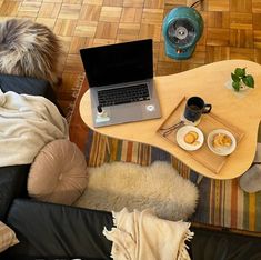 a laptop computer sitting on top of a wooden table next to a cup of coffee