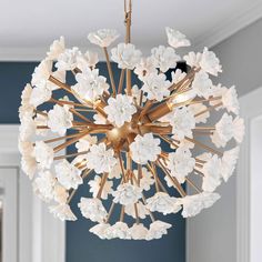 a chandelier with white flowers hanging from it's center point in a room