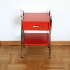 a red end table with two drawers on it and a white wall in the background