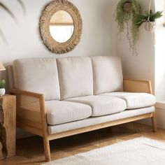 a white couch sitting in a living room next to a mirror and potted plant