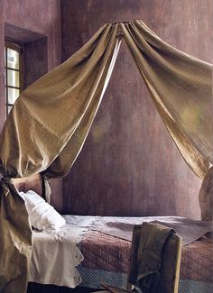 an old fashioned bed with drapes hanging over it