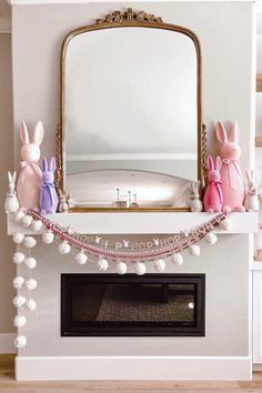 a fireplace decorated with pink and purple bunny figurines next to a mirror on the mantle