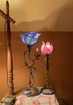 three flowers are sitting on a table next to a crochet doily and lamp