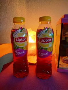 two bottles of lipton lemonade sitting on a table next to a lit candle