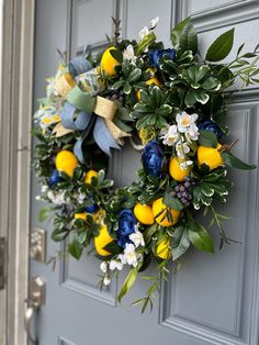 a wreath is hanging on the front door with flowers and lemons in blue, yellow and white colors