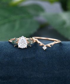 a close up view of a diamond ring on a blue velvet surface with green leaves in the background