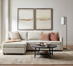 a living room with two paintings on the wall and a coffee table in front of it