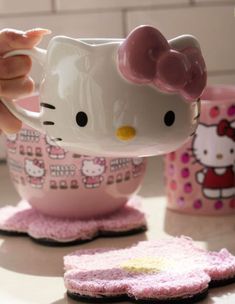 a hello kitty tea cup is being held by someone