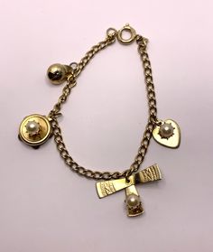 Vintage charm bracelet gold tone metal with 4 cute charms Includes a baseball cap, a heart, a tambourine, a pin wheel Spring ring clasp signed Germany 7 inches length In very good vintage condition. Light wear such as an occasional minor scratch etc... Cheap Round Vintage Charm Jewelry, Metal Charm Bracelet Costume Jewelry, Retro Metal Charms Jewelry, Vintage Gold Bracelet With Logo Charm, Vintage Yellow Gold Metal Charms, Yellow Gold Vintage Charm Metal Charms, Vintage Yellow Gold Jewelry With Logo Charm, Yellow Gold Vintage Metal Charms, Yellow Gold Metal Bracelet With Vintage Charm