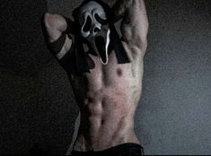 a man with no shirt holding his hands up in the air while wearing a mask