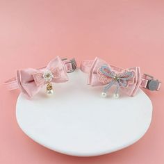 two pink bows with pearls on them sitting on a white plate against a pink background