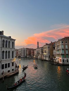 several gondolas on the water in front of buildings