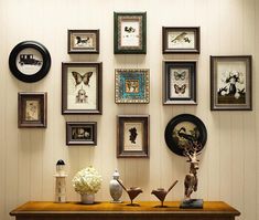 there are many framed pictures on the wall with vases and flowers in front of them